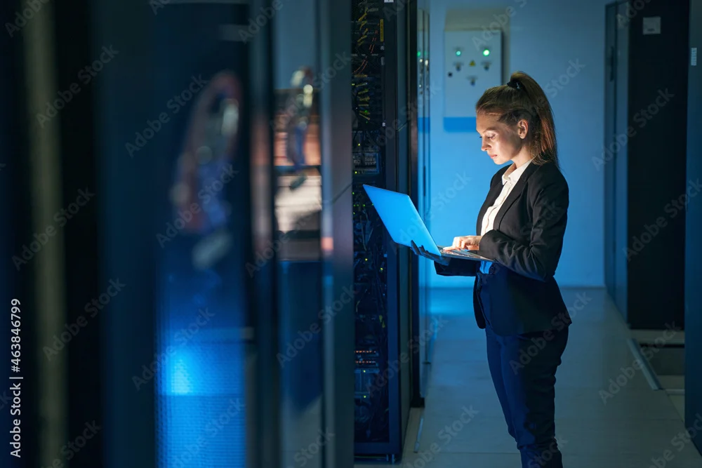 Person with a laptop in front of an open server rack in a data center