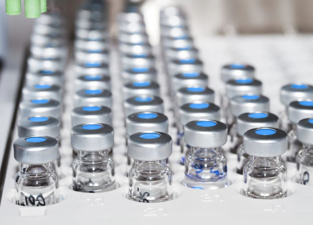 Reihen von Glasfläschchen mit silbernen Bördelkappen in einem Labortablett