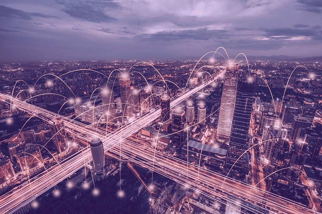 Nächtliche Stadt aus der Luft, überlagert von leuchtenden Netzwerkverbindungen