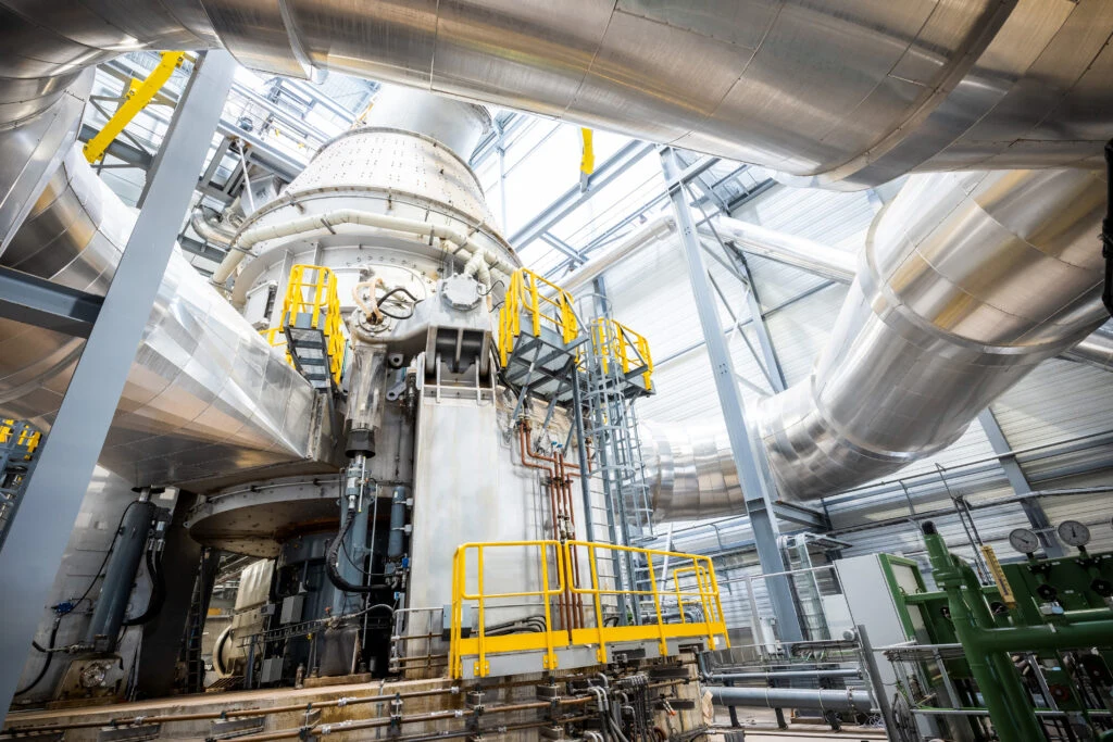 Blick in eine Industrieanlage mit Mahlanlage, Rohrleitungen und gelben Wartungsbühnen