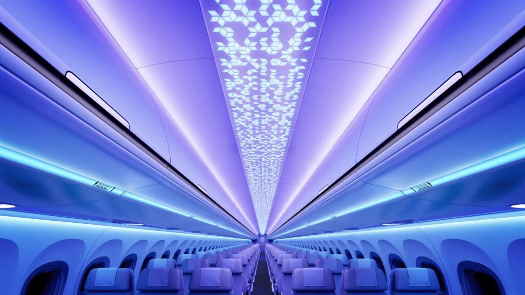 Blick durch eine Flugzeugkabine mit Sitzreihen und blau-violetter Ambientebeleuchtung