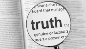 Lupe über einem Wörterbuch vergrößert den Eintrag truth
